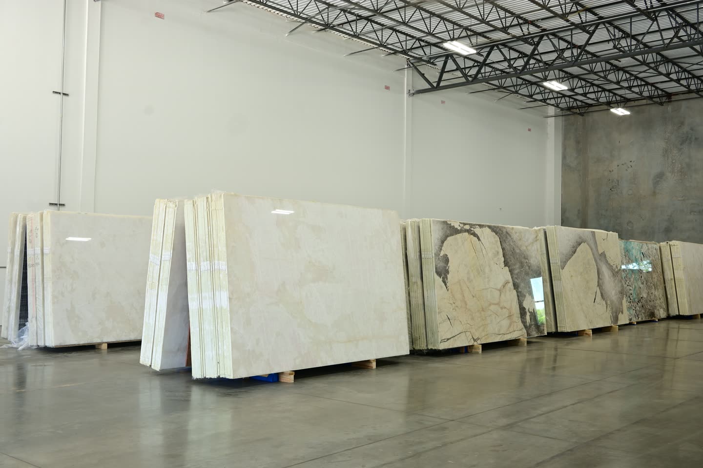 A wide view of the showroom floor with slab bundles stacked in rows along both walls.