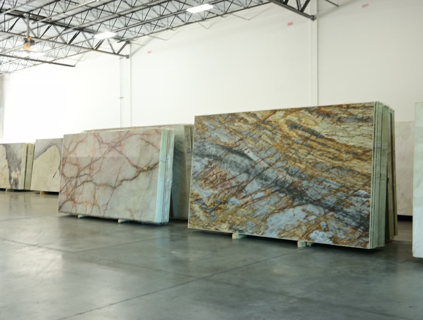 A slab with gold and blue-grey diagonal veining standing among other slabs at the showroom.