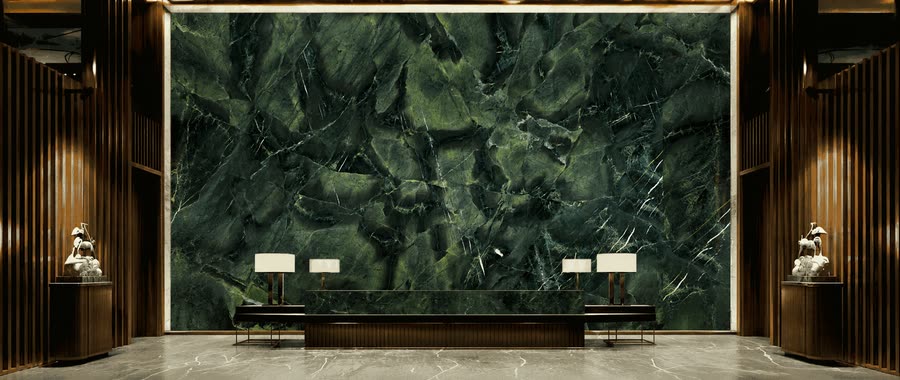 Rendered interior visualisation of a symmetrical lobby with a full-height dark green veined stone feature wall behind a long low desk, flanked by fluted panelling, backlit ceiling trim and two lit table lamps.