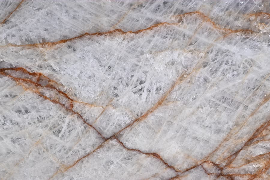 Rosso Crystallo — close view of the stone surface. Translucent white stone crossed by rust-red and amber veining.