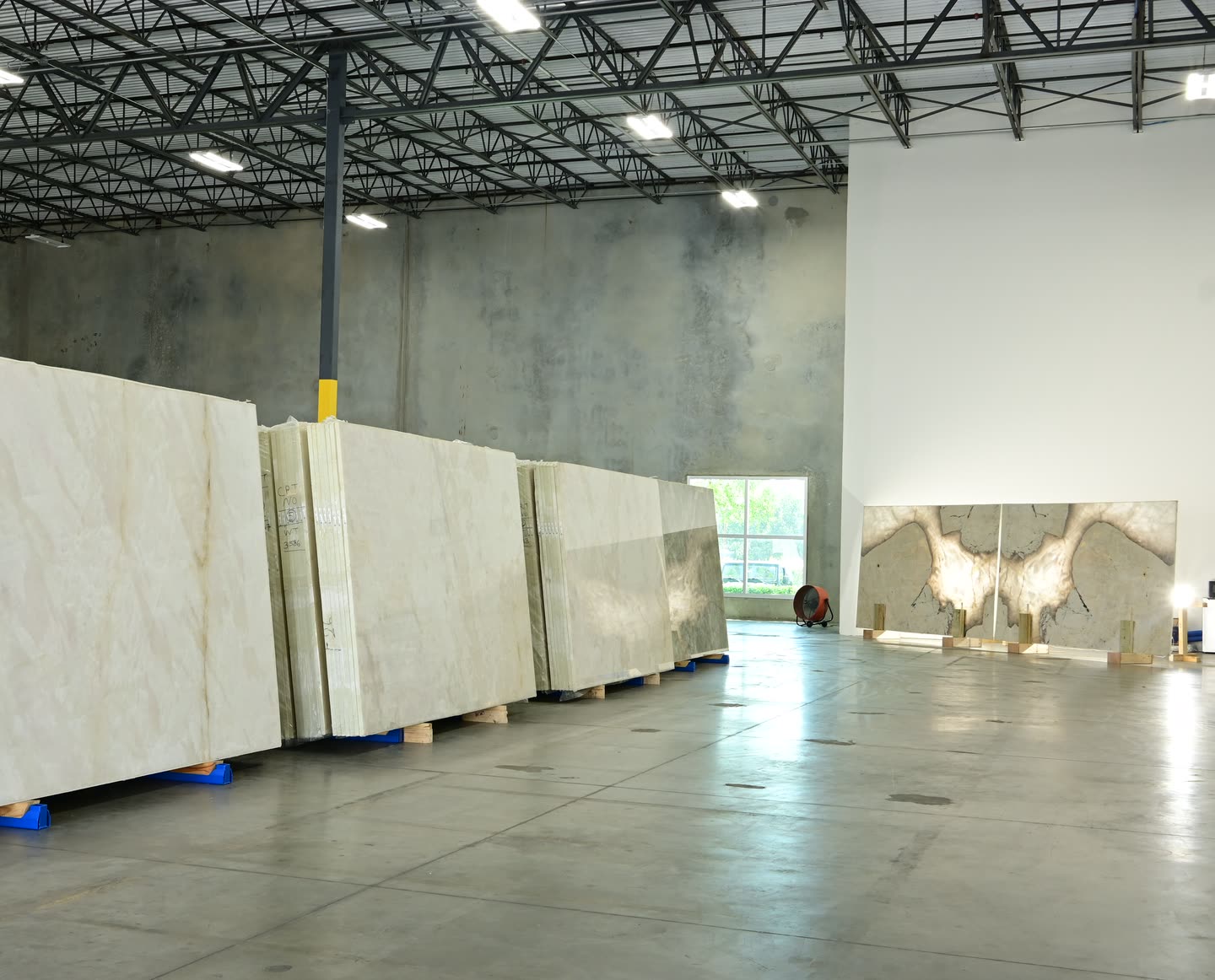 A row of cream slabs at the showroom with a mirrored dark-veined pair standing against the far wall.
